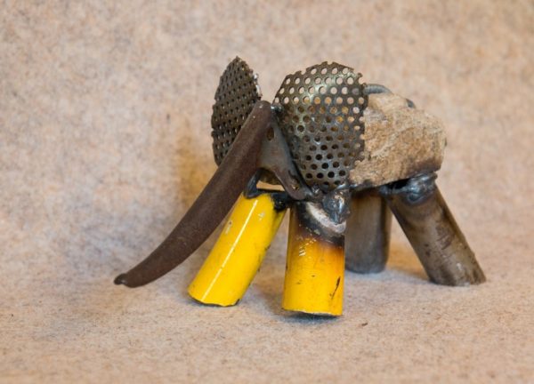 Un éléphant aux pattes jaunes en métal recyclé
