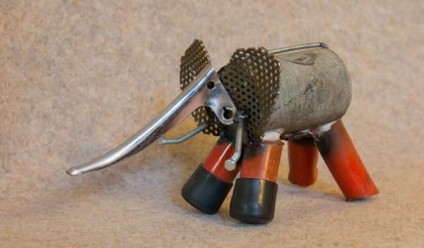 Un éléphant en métal aux pattes rouges, de profil